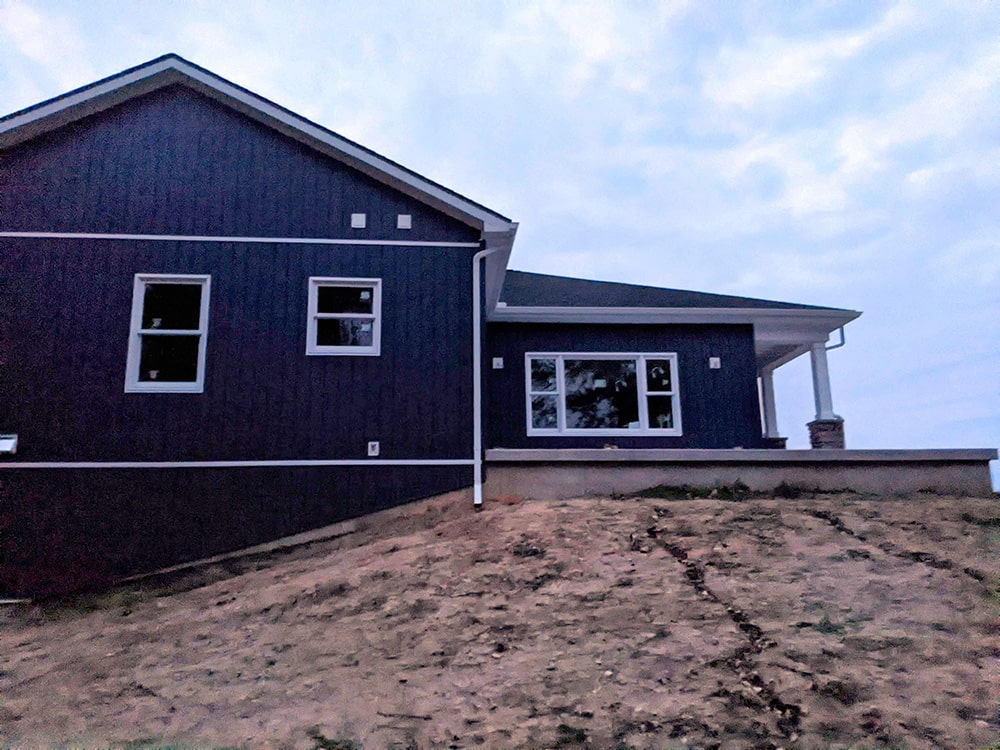Before: Image of a new residential home build with a barren, steep hill, lacking grass or landscaping.