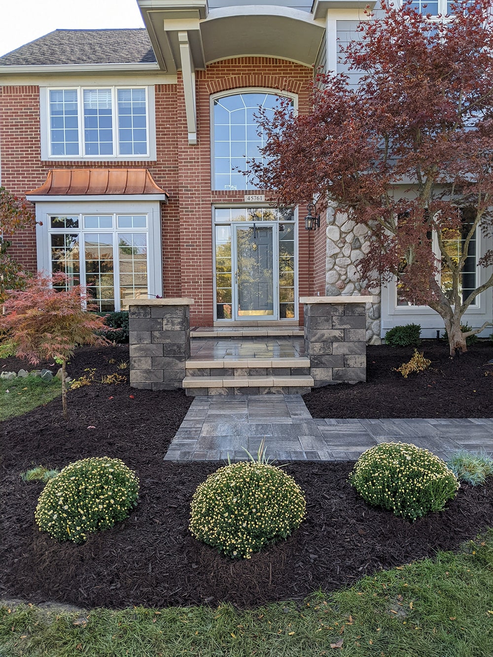 After: Image of the completed project, featuring a new stone walkway, steps, and porch area, done by BladeRunners Landscaping.