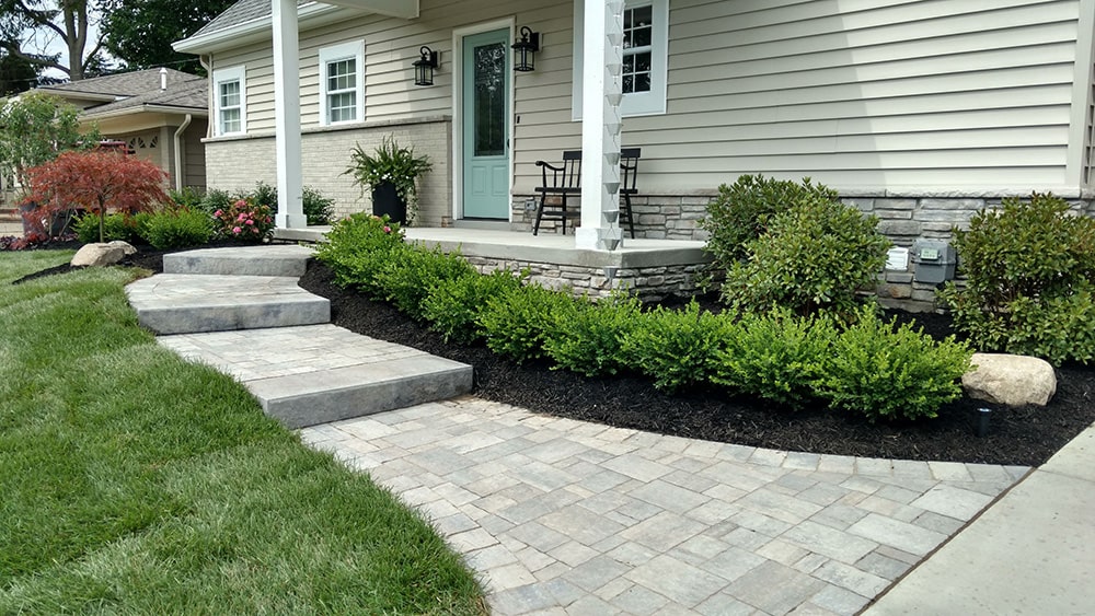 After: Image of the same home with new vinyl siding, a brick walkway, and updated landscaping.