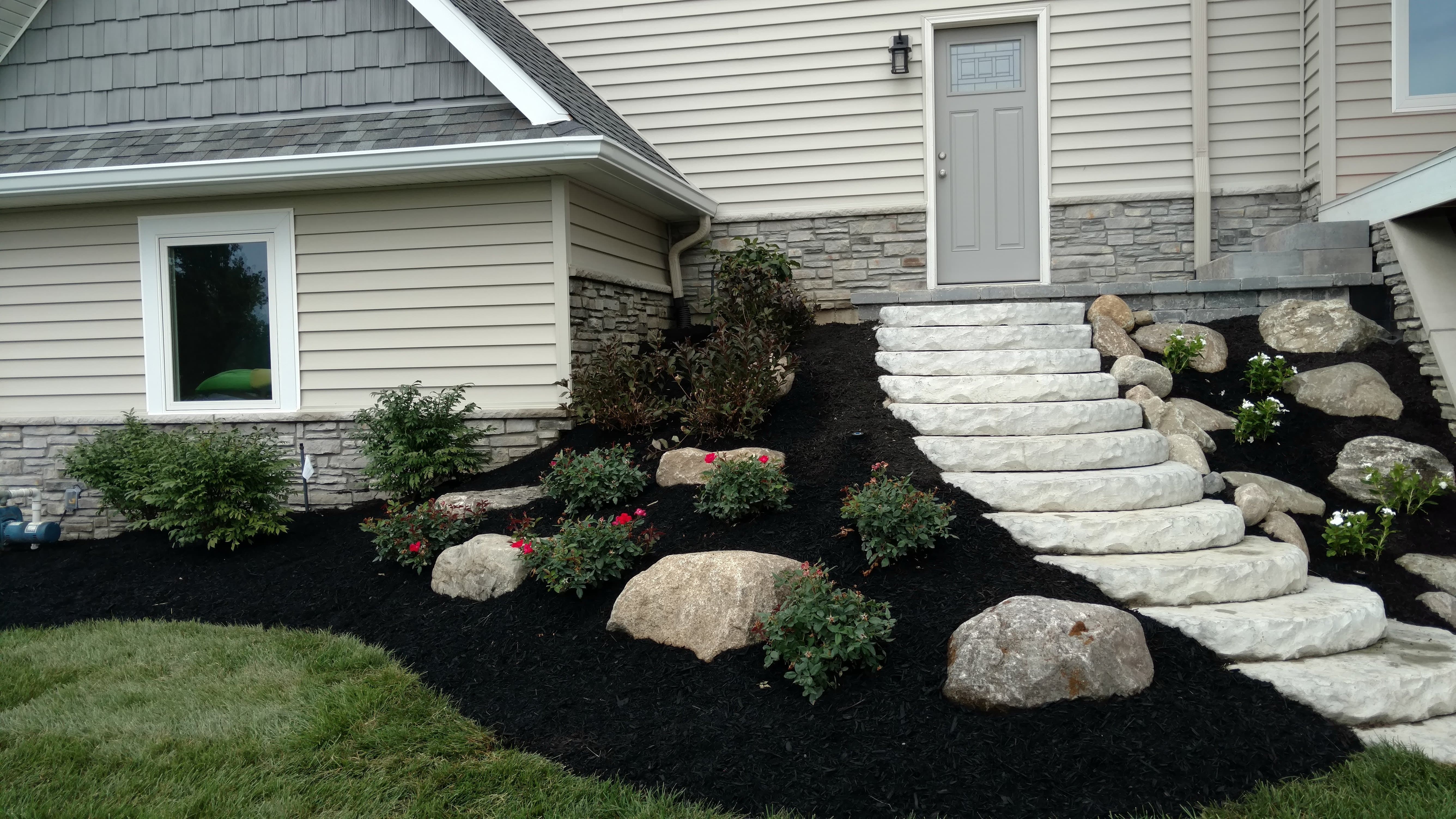 After: Image of the same home with new slab stone steps and fresh landscaping provided by BladeRunners Landscaping.