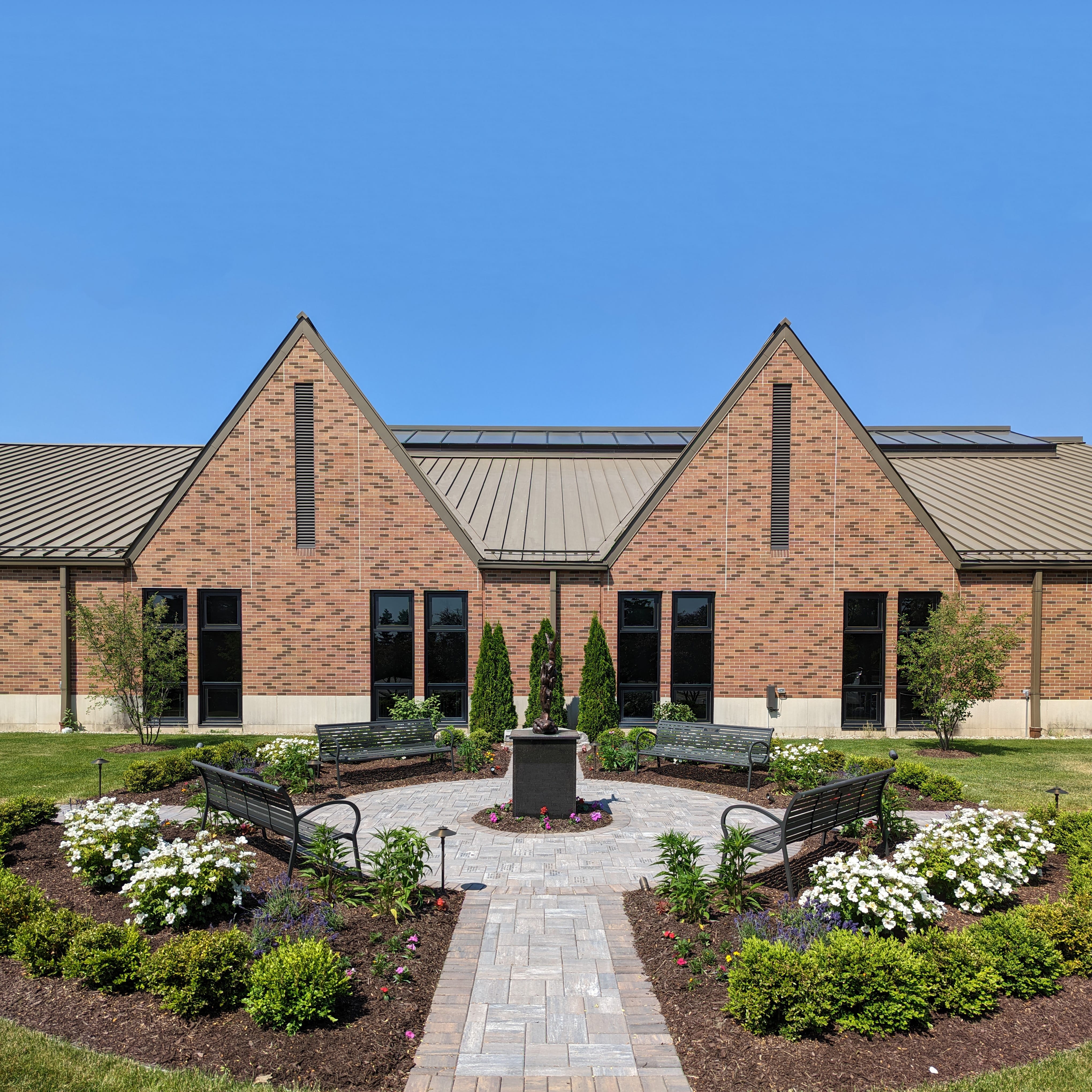 After: Image of St. James with a new brick courtyard, benches, shrubbery, and flowers, completed by BladeRunners Landscaping.